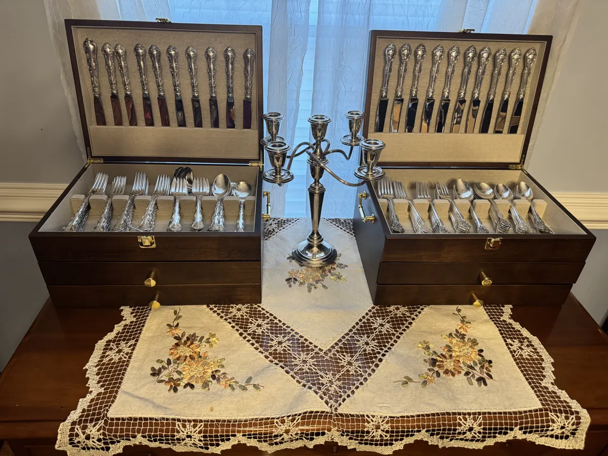 Sterling silver flatware sets and candelabra displayed in walnut cases